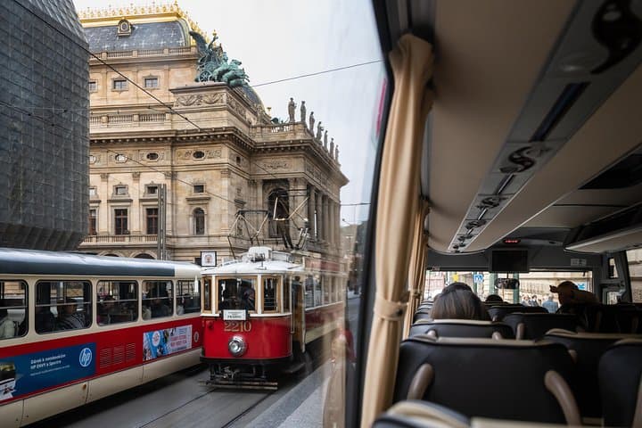 Historic trams glide past the National Theater in the center of Prague.