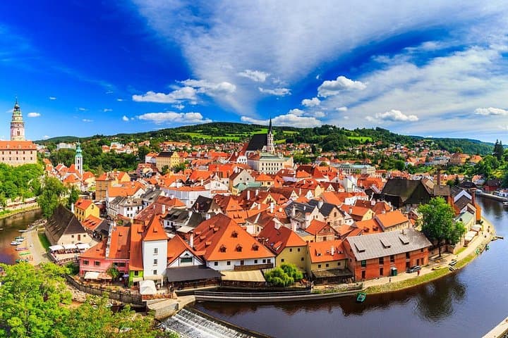 From the castle terrace, the entire town unfolds in a sweeping panorama of red rooftops, winding river, and distant green hills.