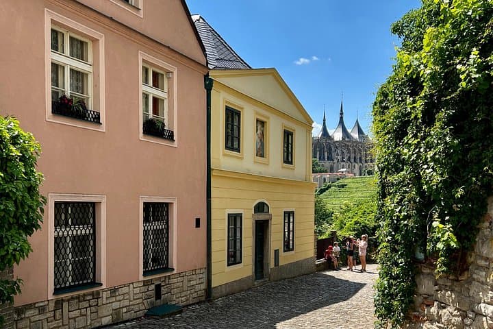 Cobblestone streets wind through the charming Old Town of Kutná Hora, lined with pastel-colored historic buildings.