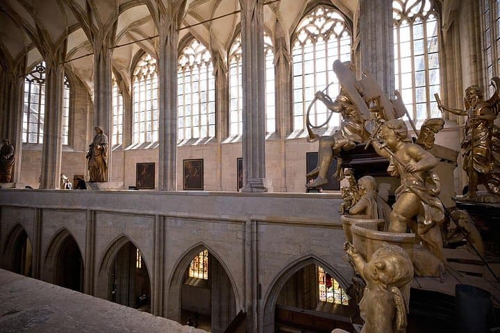 The richly decorated interior of St. Barbara’s Cathedral showcases stunning frescoes, ribbed vaults, and gothic elegance.