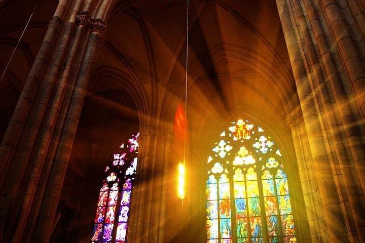 Inside the St. Vitus Cathedral with sunlight shining through the ornate stained-glass