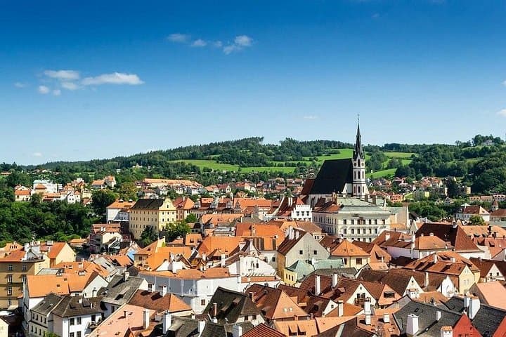 The spire of St. Vitus Church cuts sharply into the skyline, its dark roof contrasting the warm earth tones below.